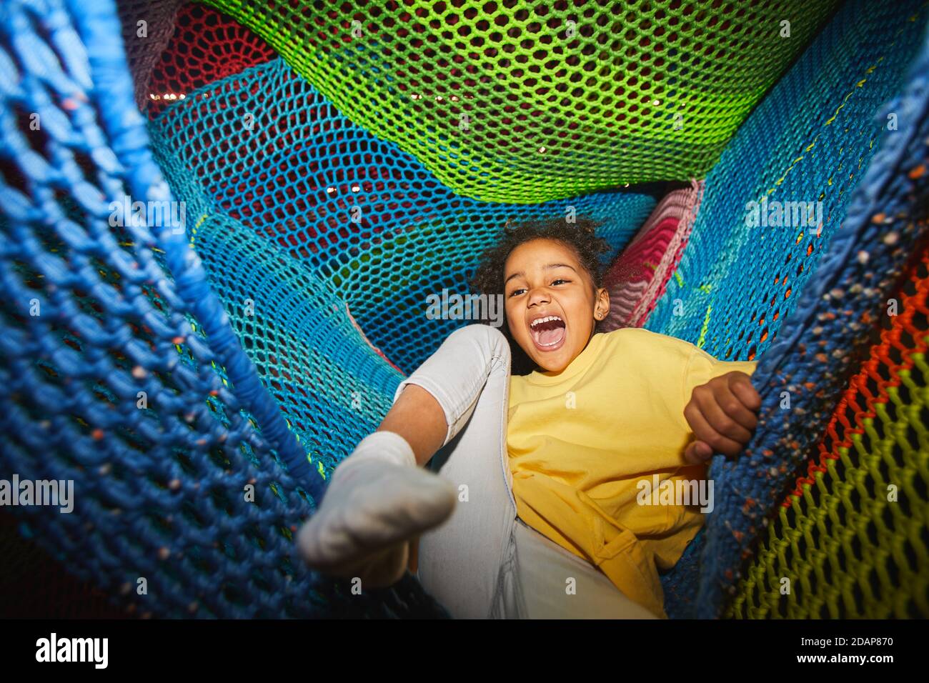 Aufgeregt afrikanisches Mädchen, das Spaß in der Hängematte im Indoor-Vergnügen hat parken Stockfoto