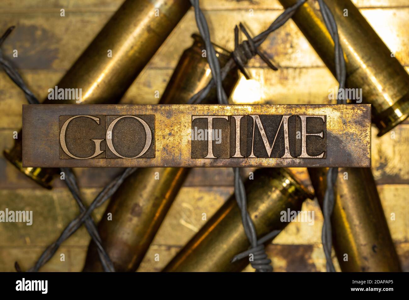 Go Time Text gebildet mit echten authentischen Satzbuchstaben auf 50 Kaliber BMG Geschossgehäuse mit schwarzem Hintergrund mit abgedeckt Stacheldraht Stockfoto