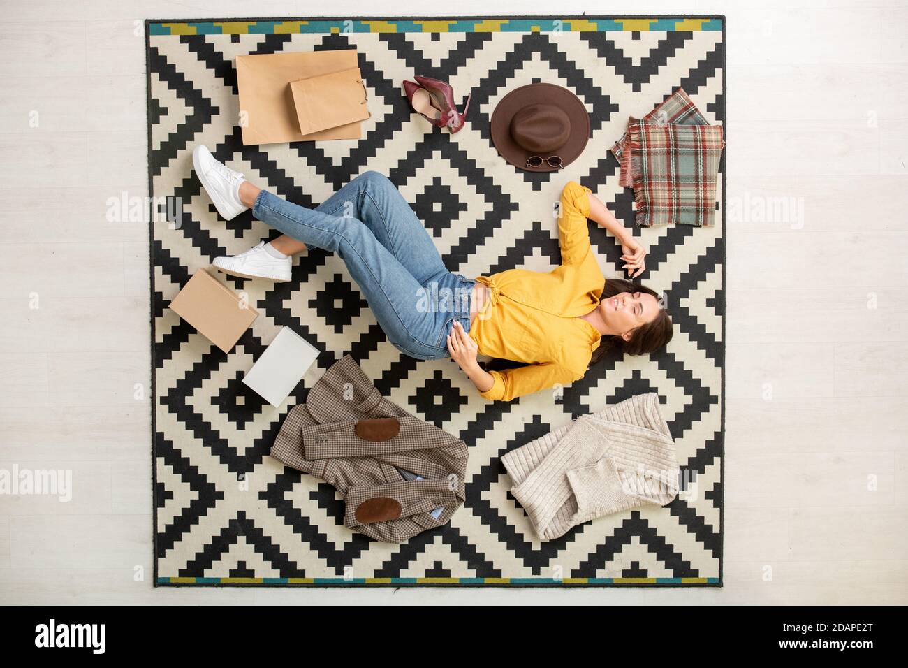 Blick auf junge glückliche Frau umgeben von neuen smart Casualwear Auf dem Teppich liegend Stockfoto