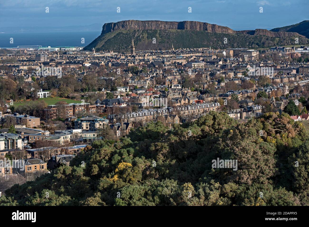 Wohnhäuser in Süd-Edinburgh mit Salisbury Crags im Hintergrund, aufgenommen aus Blackford Hill, Edinburgh, Schottland, Großbritannien. Stockfoto