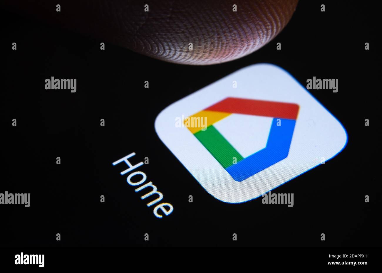 Stafford / Vereinigtes Königreich - November 12 2020: Google Home App und verschwommene Fingerspitze darüber bereit, den Bildschirm des Smartphones zu drücken. Stockfoto