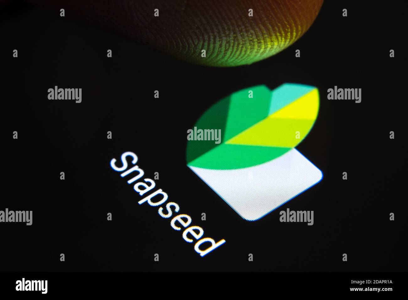 Stafford / Großbritannien - November 12 2020: Snapseed App und verschwommene Fingerspitze darüber bereit, den Bildschirm des Smartphones zu drücken. Stockfoto