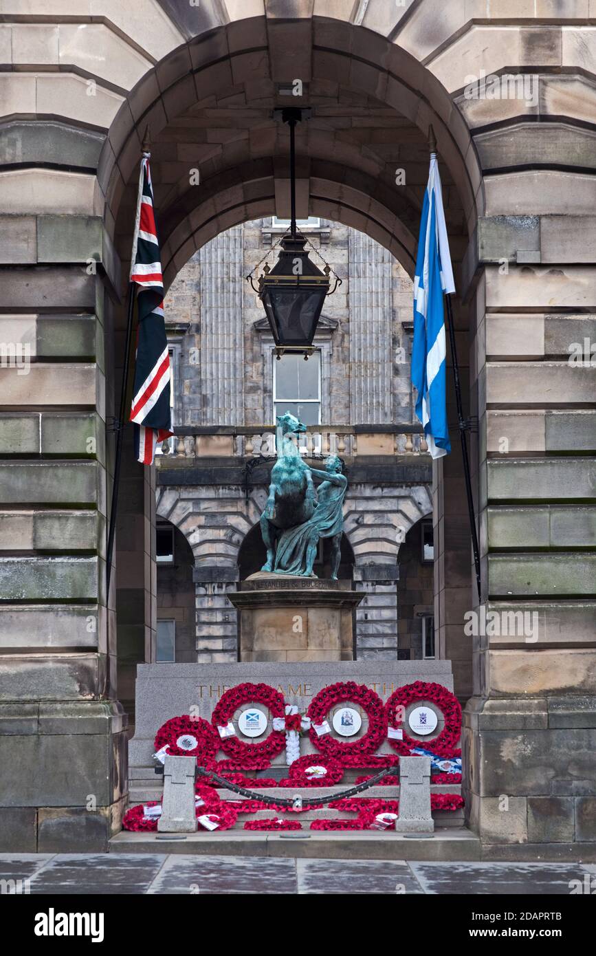 Mohnkränze und der Stein der Erinnerung vor den City Chambers in Edinburgh zusammen mit der Union Jack und der Scottish Saltyre Flagge. Stockfoto