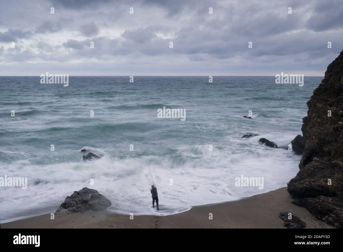 Nicht erkennbarer Fischer Mann mit Angelrute im Wasser mit starken Wellen eingetaucht. Stockfoto