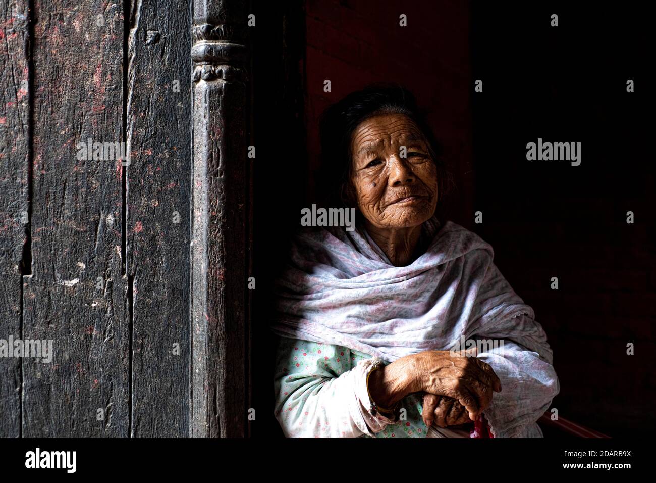 Porträt einer älteren Frau, die aus einer Tür schaut, Patan, Lalitpur, Kathmandu, Nepal Stockfoto