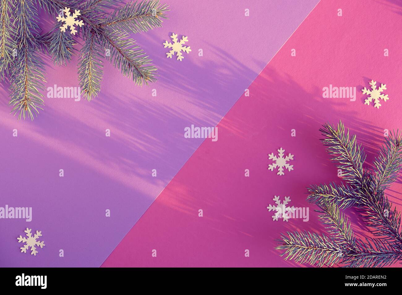 Weihnachten, Neujahr Hintergrund in zwei Ton rosa und lila. Tannenzweige mit Papier Schneeflocken, Konfetti. Kein Plastik, umweltfreundliche Dekorationen. Trendiges fl Stockfoto