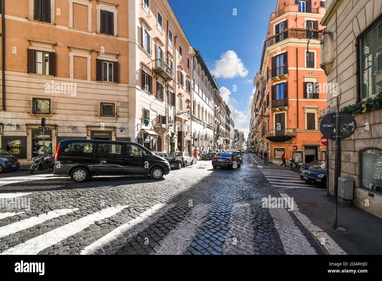 Fußgängerverkehr und Autos auf einer belebten Kopfsteinpflasterstraße nur Außerhalb des historischen Zentrums von Rom Italien Stockfoto