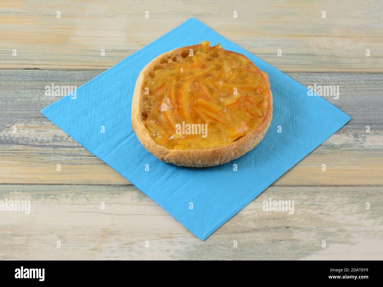 Orangenmarmelade auf Vollkorn Englische Muffin Hälfte auf blau Serviette auf dem Tisch Stockfoto