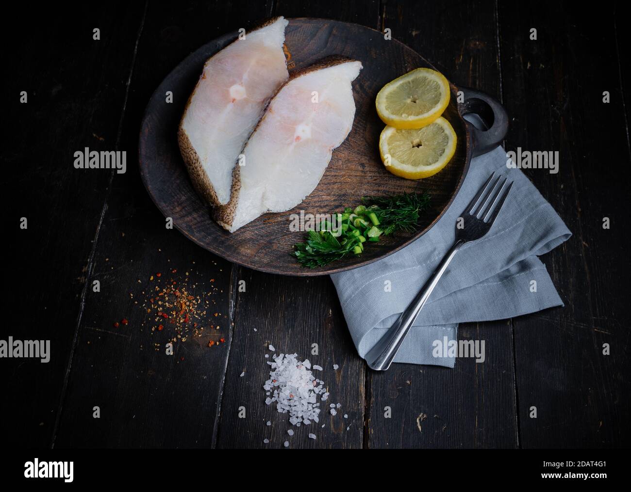 Gefrorene grönländische Heilbutt-Steaks auf dem Holzschneidebrett. Hintergrund für das Essen. Draufsicht Stockfoto