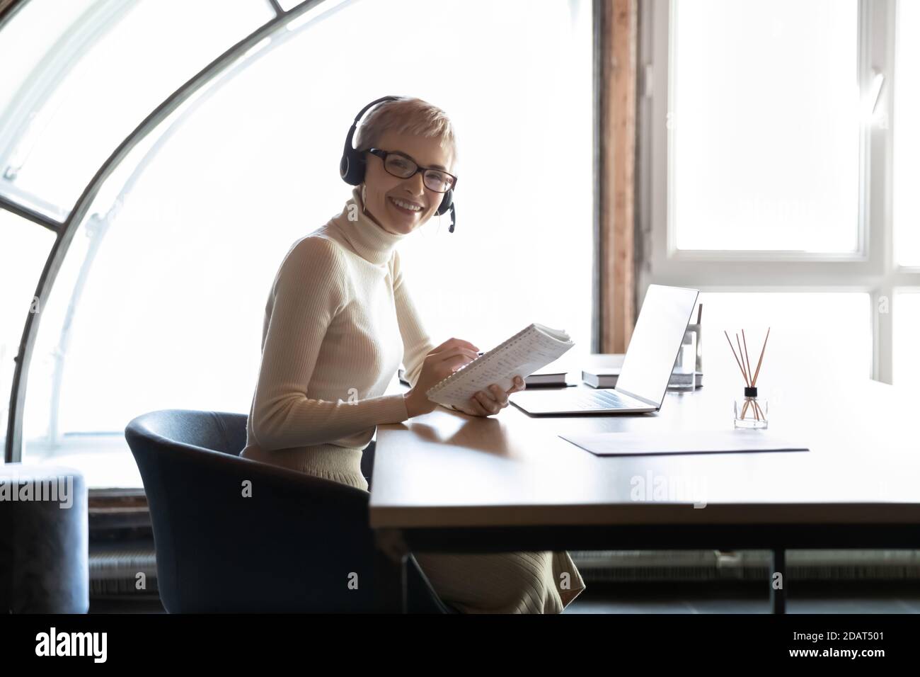 Lächelnde Geschäftsfrau mit Headset am Schreibtisch Stockfoto