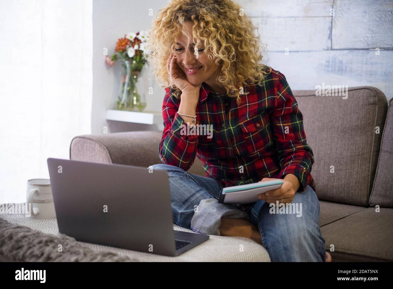Schöne fröhliche Frau arbeiten zu Hause mit Laptop-Computer sitzen Auf dem Sofa lächelnd auf dem Display - Videoanruf Konferenz- und Smart-Working-Job li Stockfoto