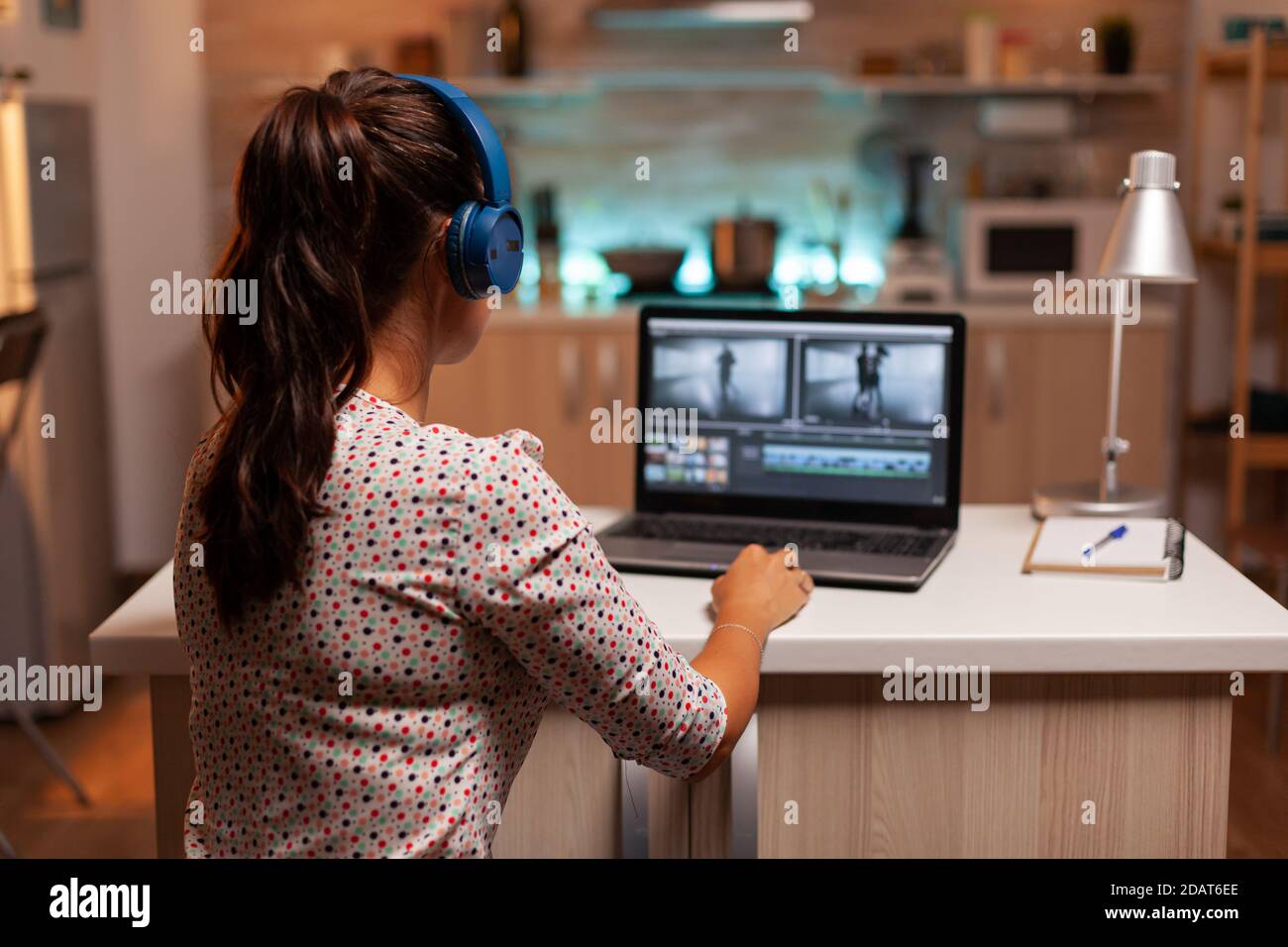 Video-Editor arbeitet an einem Projekt aus der Küche zu Hause in der Nacht Zeit und Musik auf Kopfhörer hören. Content Creator zu Hause arbeiten an Montage von Film mit moderner Software für die Bearbeitung. Stockfoto
