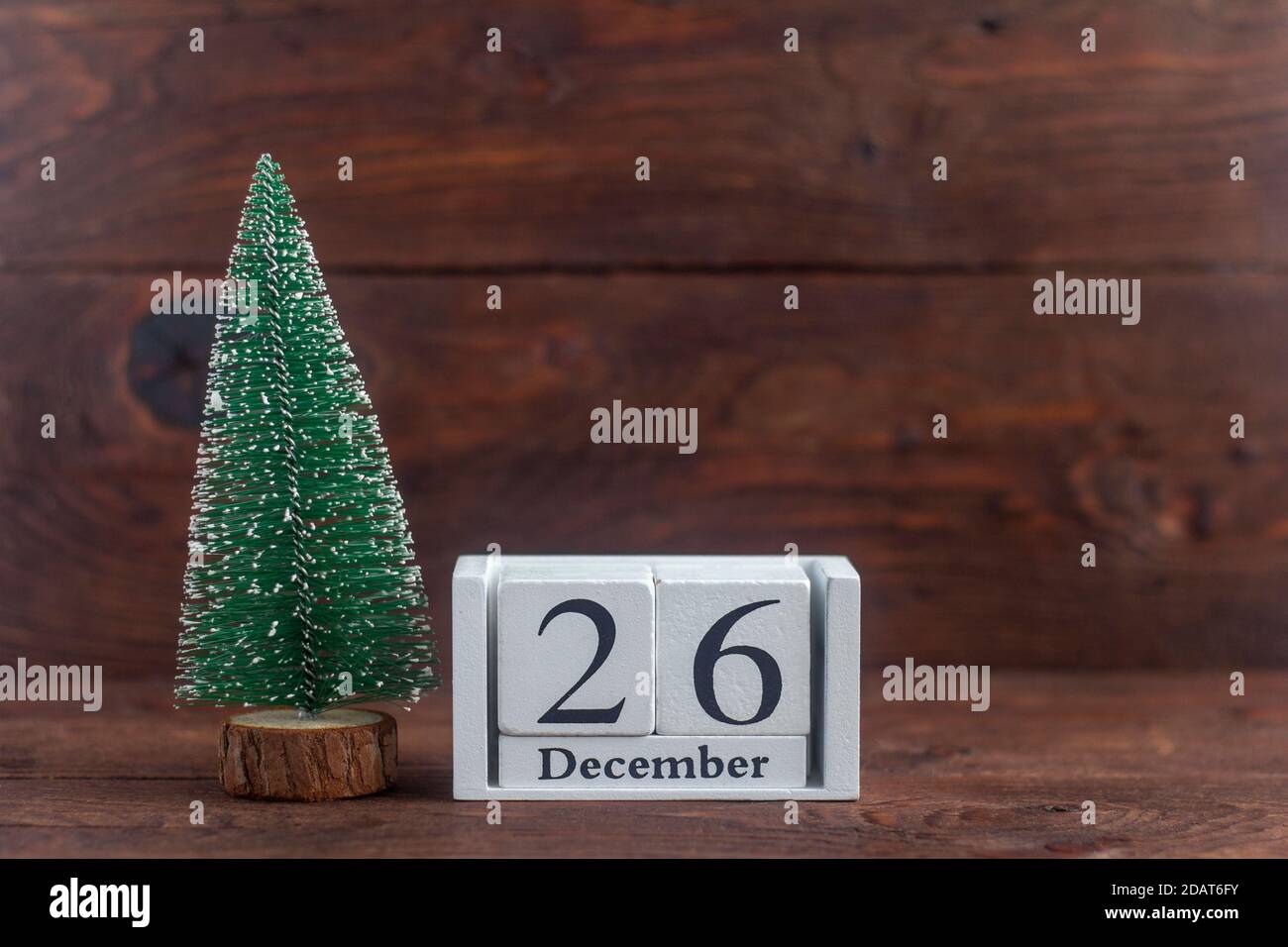 Dezember 26 auf dem Kalender.Kalender mit einem kleinen Weihnachtsbaum auf einem hölzernen Hintergrund. Winter. Leeres Leerzeichen für Text. Stockfoto