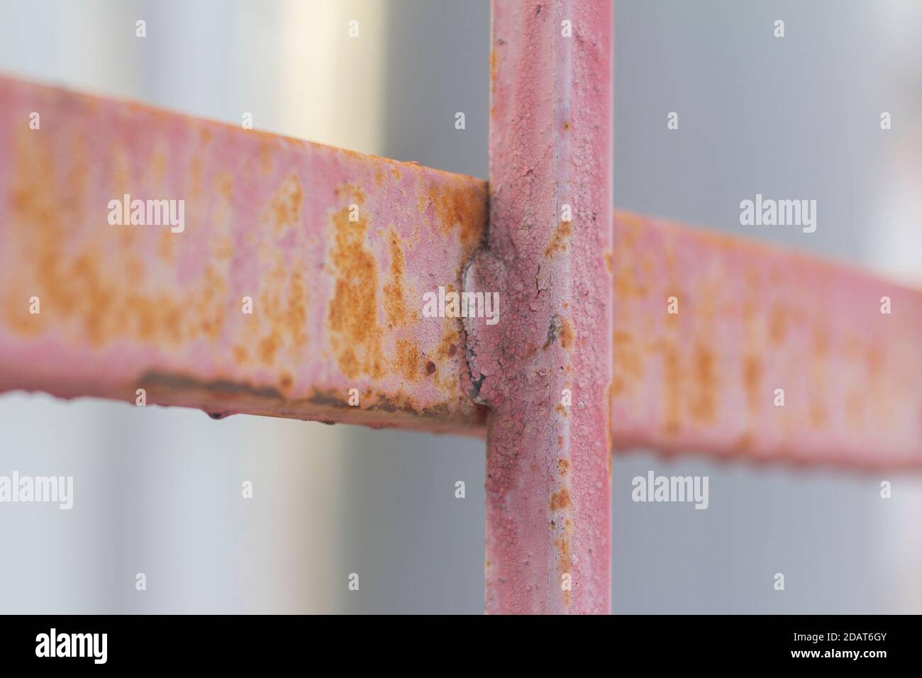 Fragment eines Metallzauns mit Rostflecken durch rosa Farbe Stockfoto