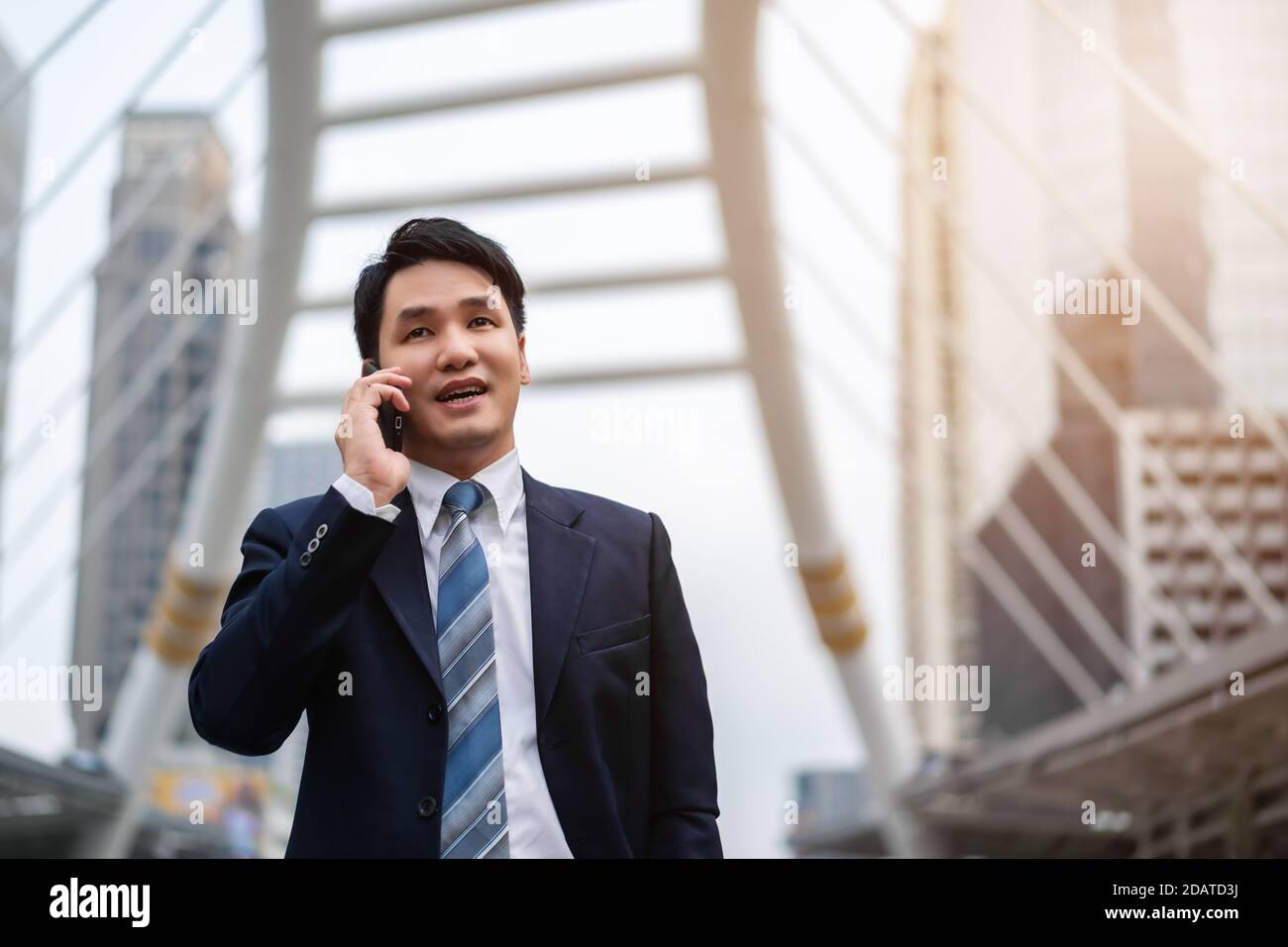 Erfolgreicher Geschäftsmann im Anzug, der ein Mobiltelefon anspricht Die Stadt Stockfoto
