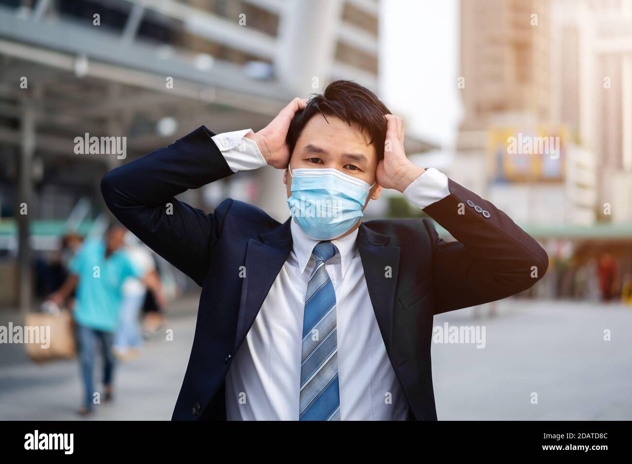 Gestresster Geschäftsmann mit medizinischer Maske während einer Coronavirus-Pandemie (covid-19) In der Stadt Stockfoto