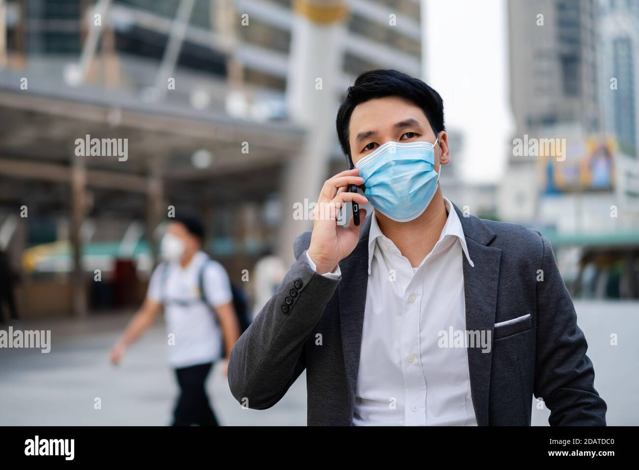 Geschäftsmann, der mit dem Handy spricht und eine medizinische Maske trägt Während Coronavirus (covid-19) Pandemie in der Stadt Stockfoto