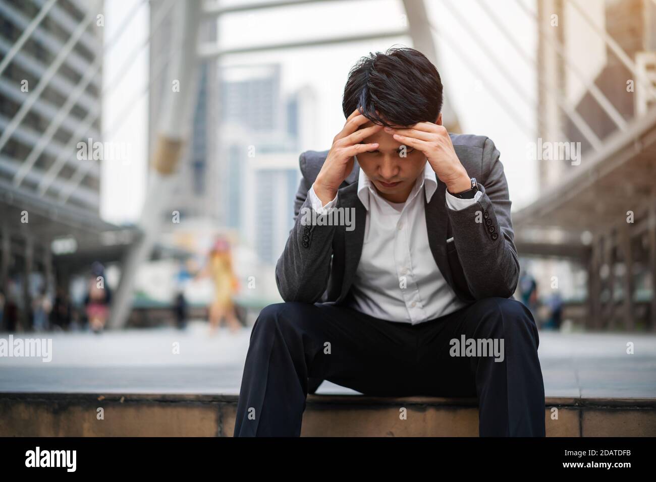 Gestresster Geschäftsmann sitzt auf dem Boden in der Stadt Stockfoto
