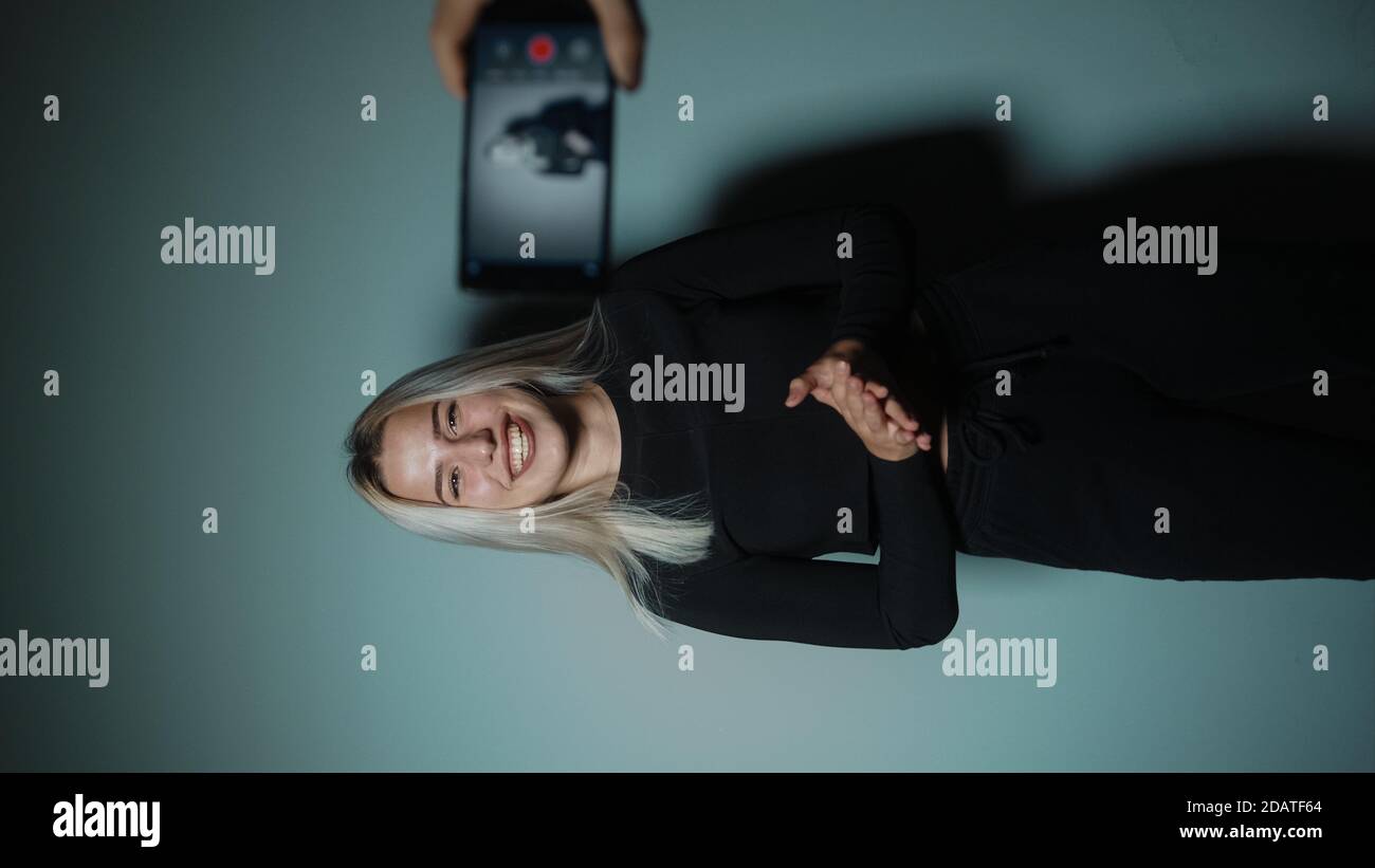 Junge blonde schöne attraktive Frau nimmt Video vlog Mit Telefon in Cyan-Farbe Studio-Hintergrund Stockfoto
