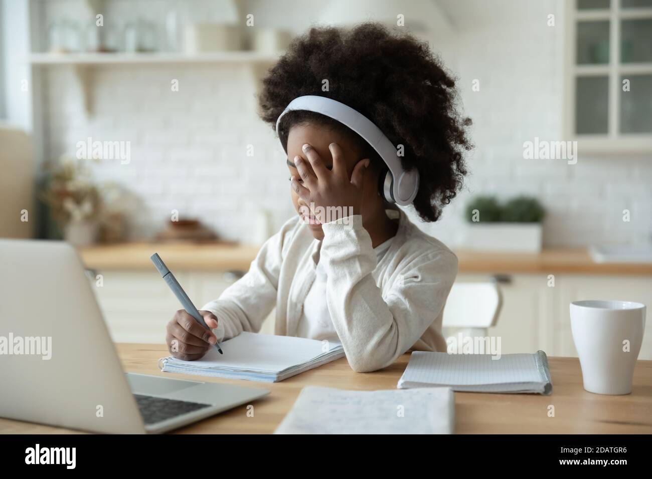 Müde afroamerikanische kleine Mädchen trägt Kopfhörer studieren online Stockfoto