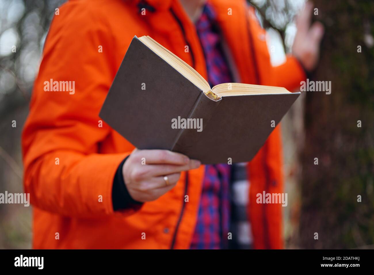 Nahaufnahme der Hand des Menschen mit Buch. Nicht erkennbarer Mann hält Buch, im Wald stehend Stockfoto