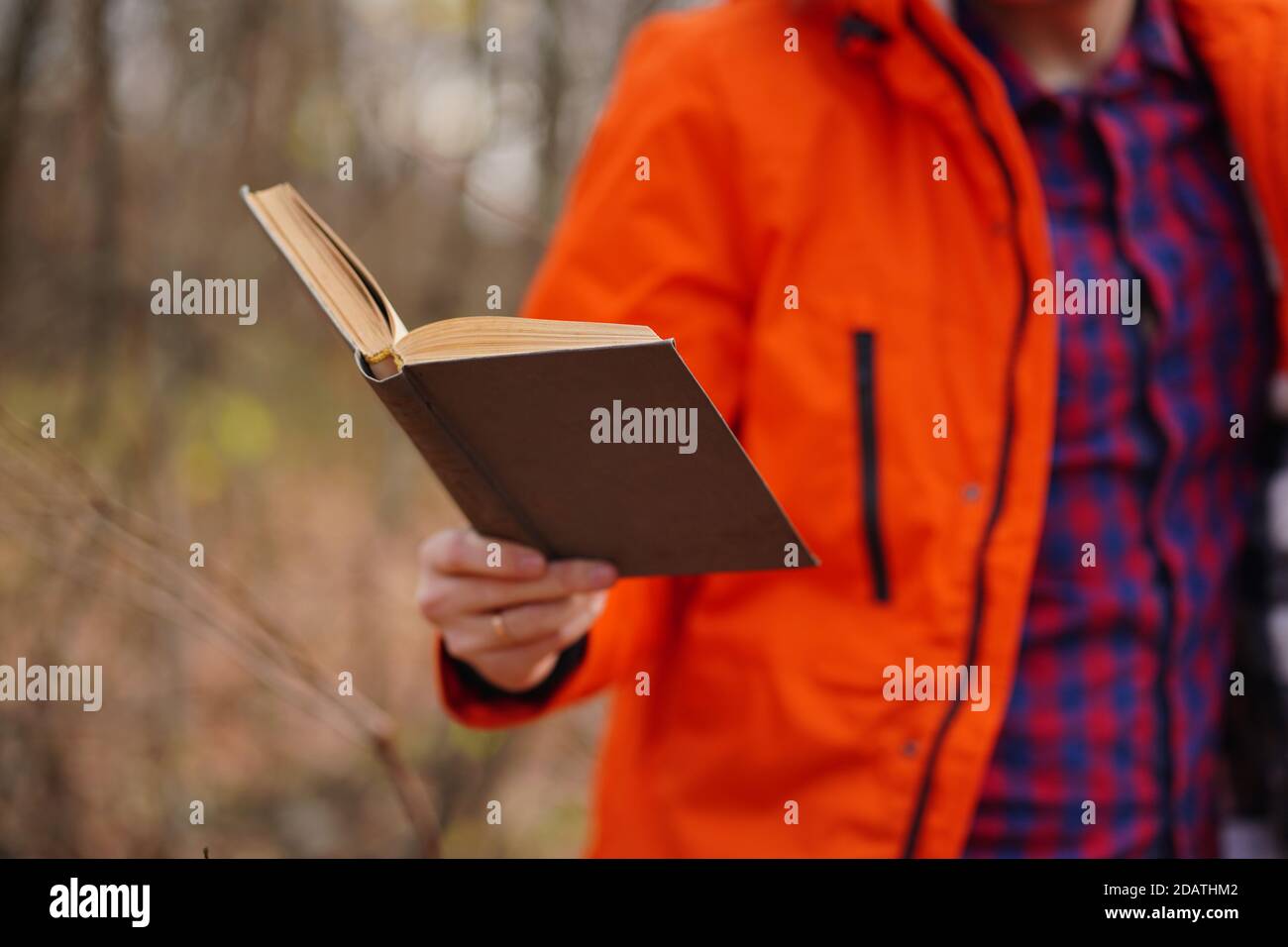 Nahaufnahme der Hand des Menschen mit Buch. Nicht erkennbarer Mann hält Buch, im Wald stehend Stockfoto