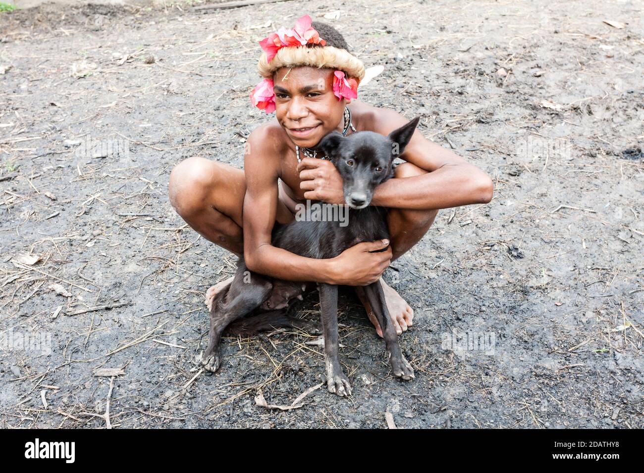 Wamena, Indonesien - 9. Januar 2010: Mann des Dani-Stammes sitzt mit Hund, Dugum Dani Village, Indonesisch-Neuguinea Stockfoto