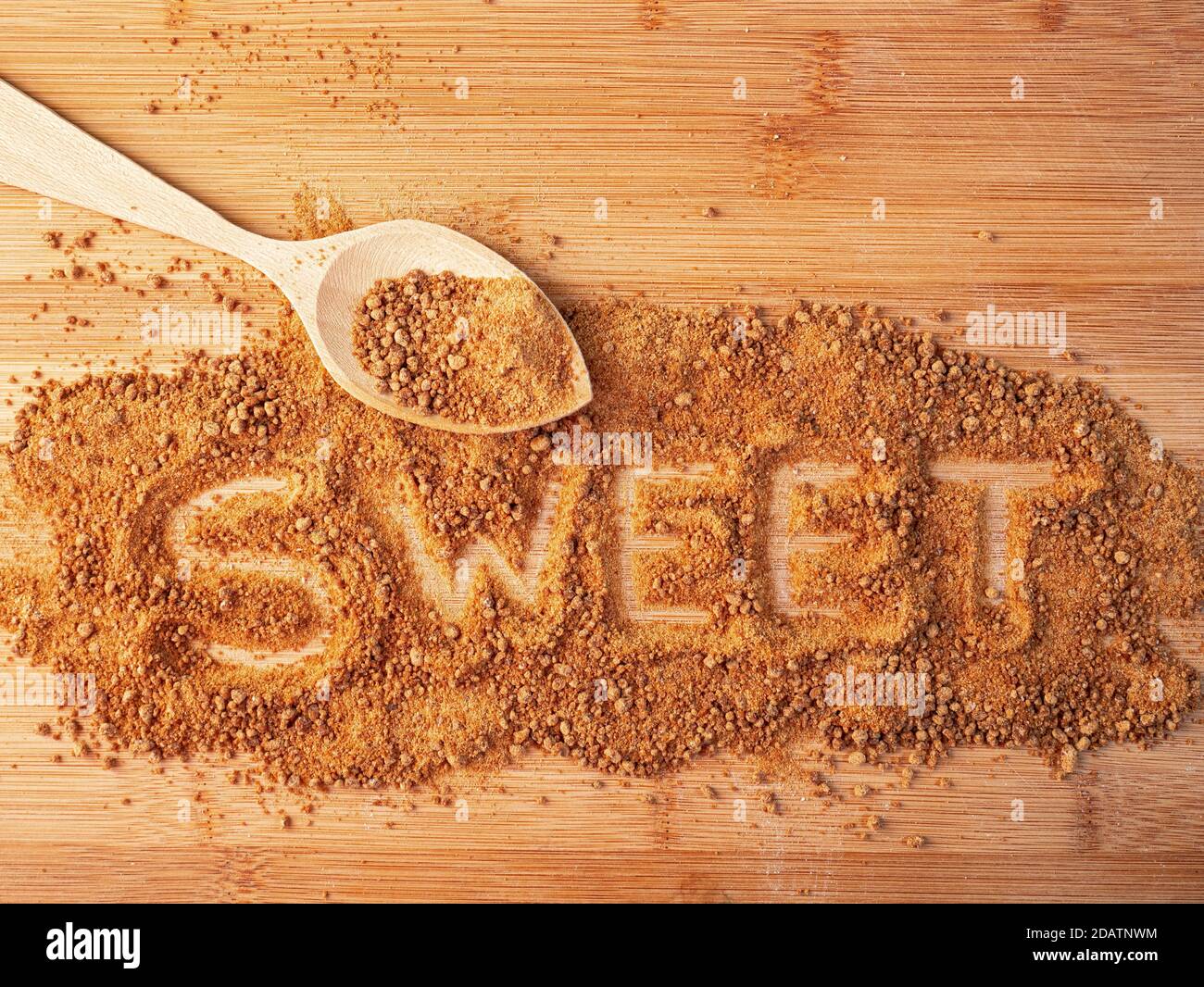 Das Wort "SÜSS" ist mit Krümel auf einer hölzernen Oberfläche geschrieben Stockfoto