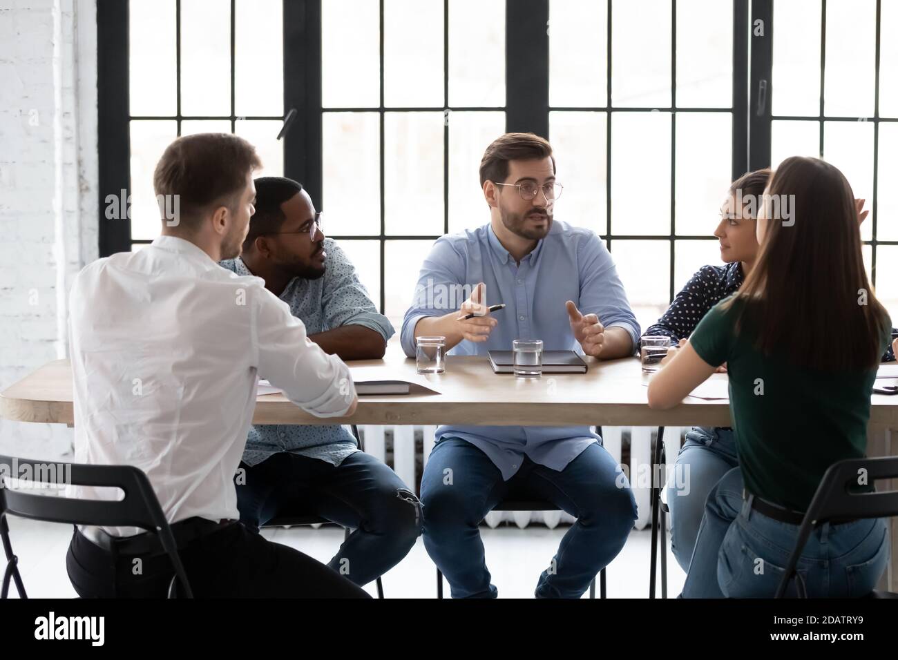 Geschäftsteam aus fünf Millennials-Mitgliedern beim Brainstorming im Sitzungssaal des Büros Stockfoto