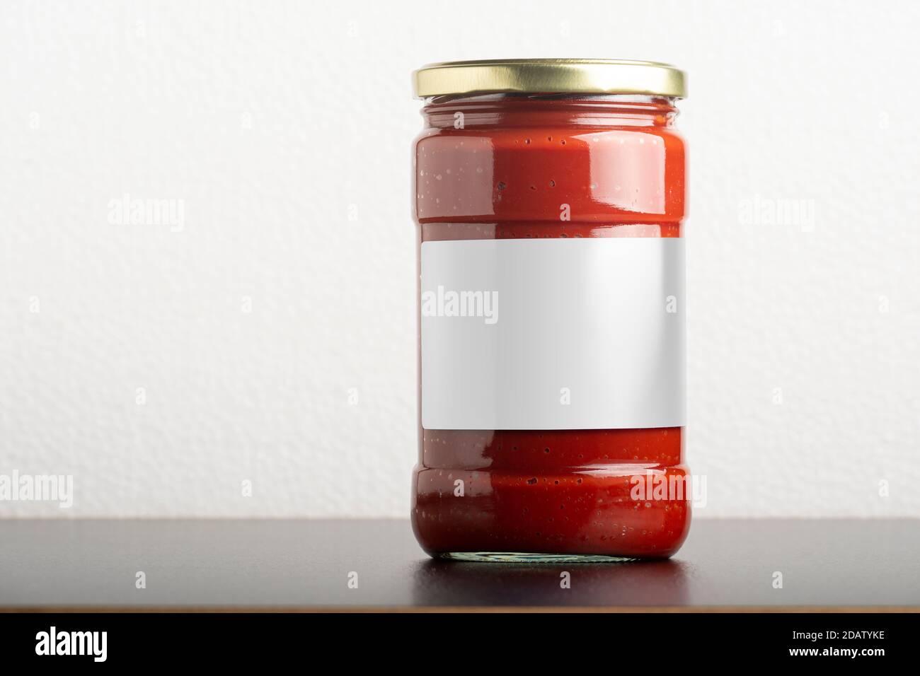 Tomatenmark Glasglas mit runder Kappe auf schwarzem Tisch, bearbeitbare Modell-up-Serie Vorlage bereit für Ihr Design, Label-Auswahl-Pfad enthalten. Stockfoto