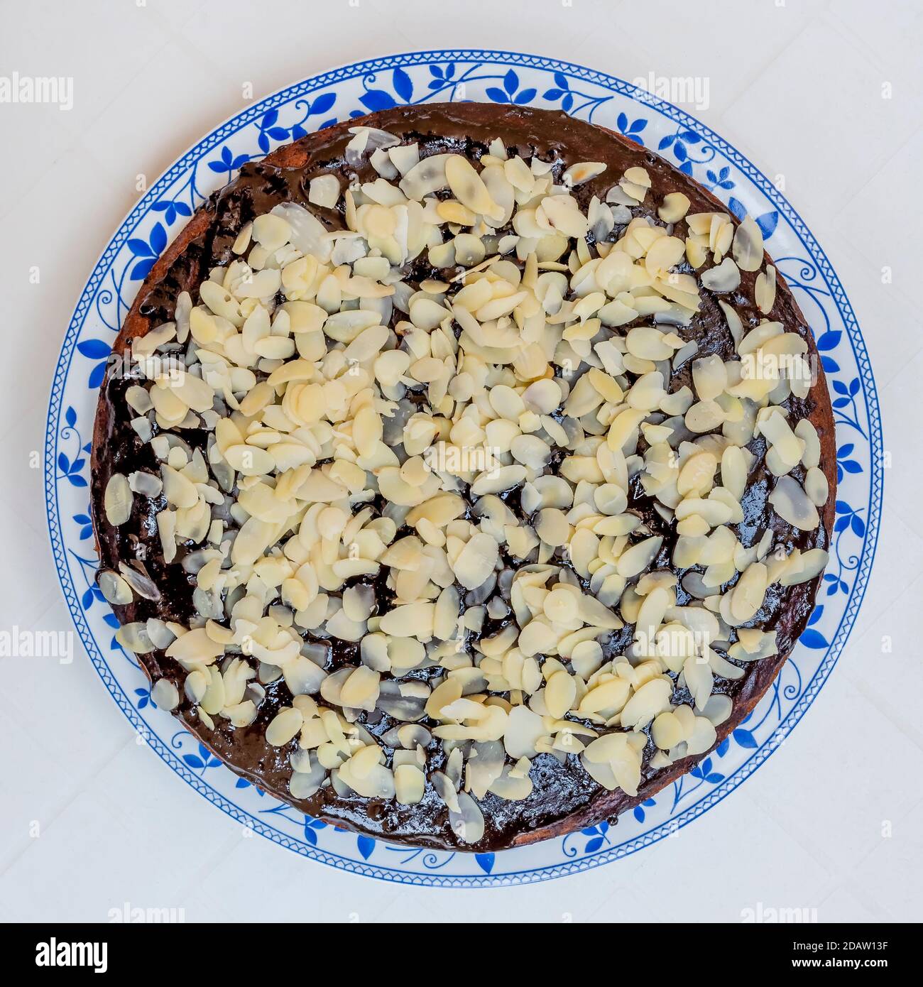 Kakao- und Kokosnusskuchen mit Schokoladenglasur und Mandelflocken auf weißem Hintergrund Stockfoto