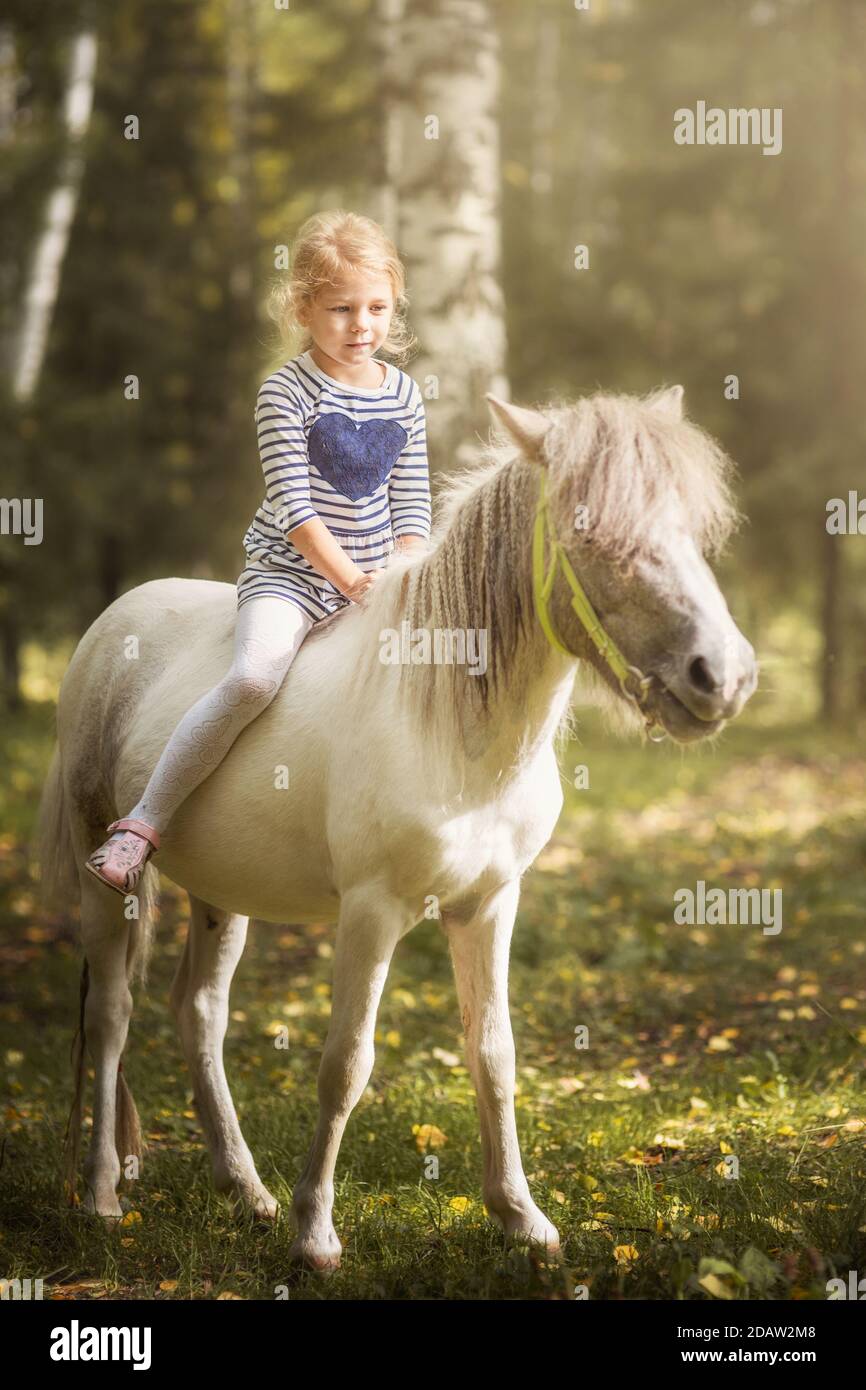 Kleine blonde Mädchen Reiten kleinen Pferd Pony Stockfoto