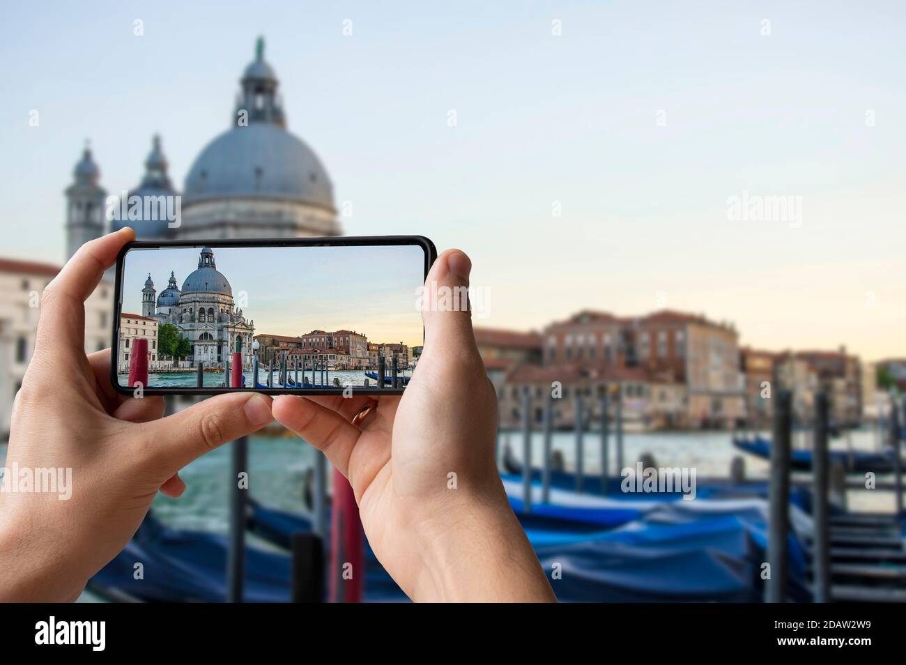 Tourist Foto von traditionellen Gondeln auf dem berühmten Canal Grande mit der historischen Basilika Santa Maria della Salute im Hintergrund in Venedig, Es Stockfoto