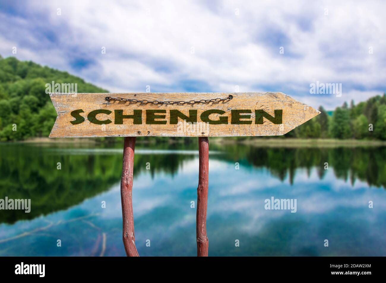 Schengen Holzpfeil Straßenschild gegen See und Wald Hintergrund. Schengen - Europäischer Grenzkontrollraum Stockfoto