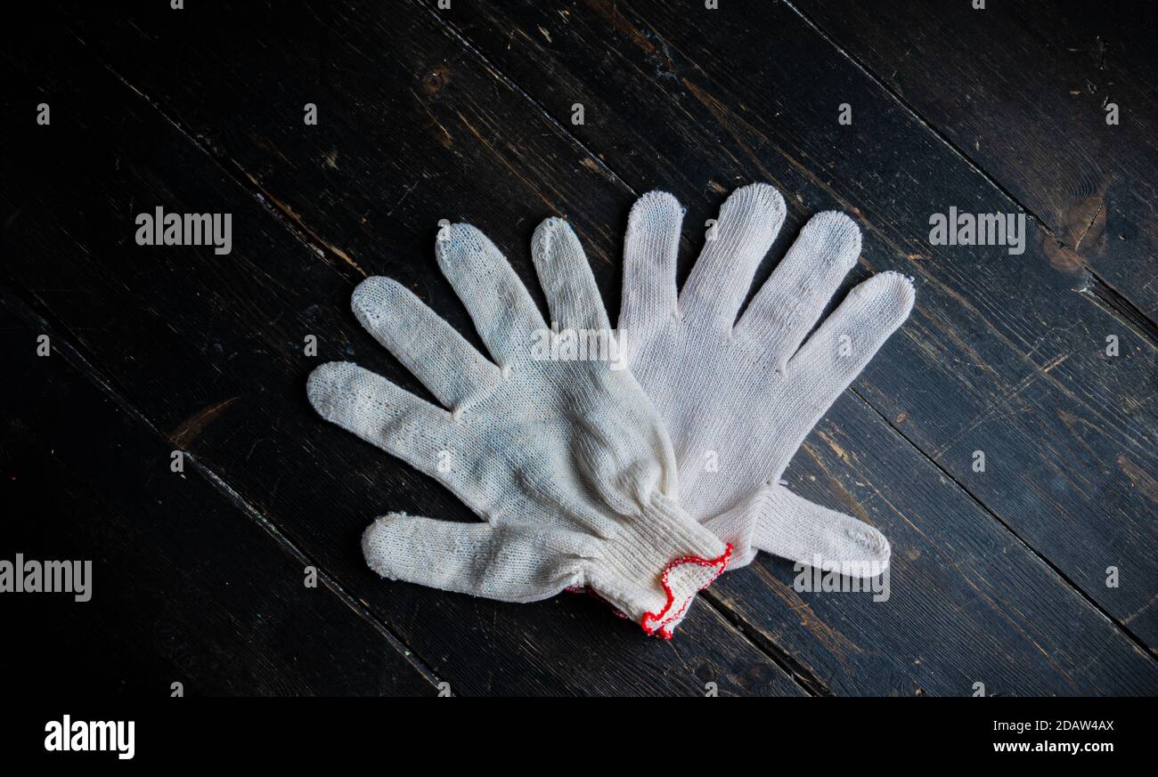 Neue Arbeitshandschuhe auf dunklem Holztisch. Ein Paar Baumwollhandschuhe Stockfoto