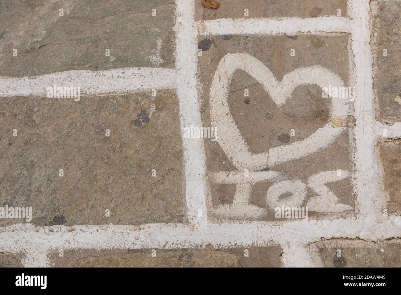 Steinpflaster Textur, Hintergrund. Gelenke weiß lackiert, iOS Insel Name auf einer Fliese, Griechenland. Stockfoto