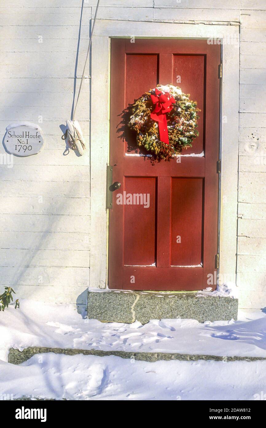 Ein Weihnachtskranz hängt an einer roten Tür in Phillipston, Massachusetts Stockfoto