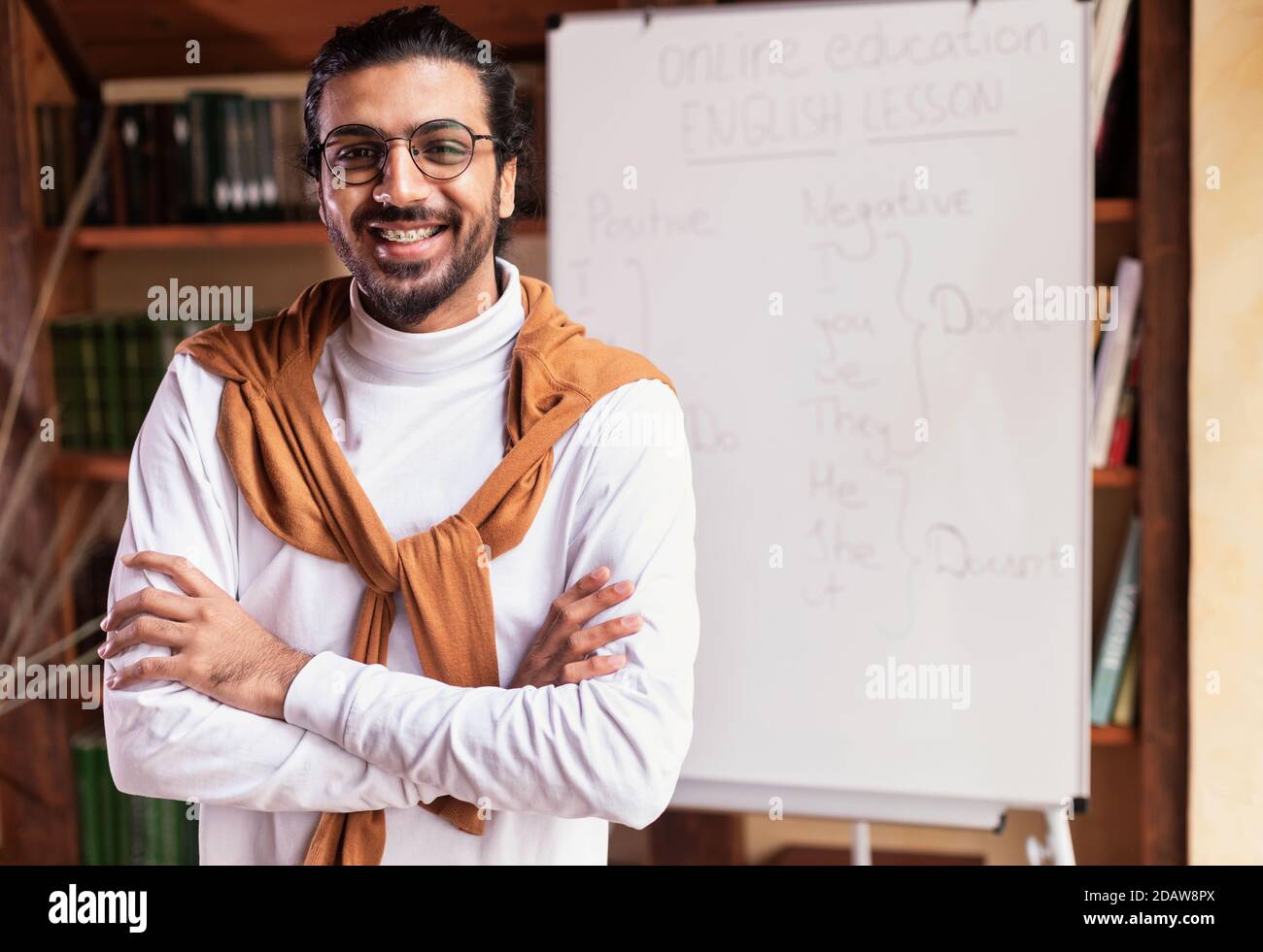 Lächelnder Indischer Lehrer Guy Posiert In Der Nähe Von Blackboard Stehend Zu Hause Stockfoto