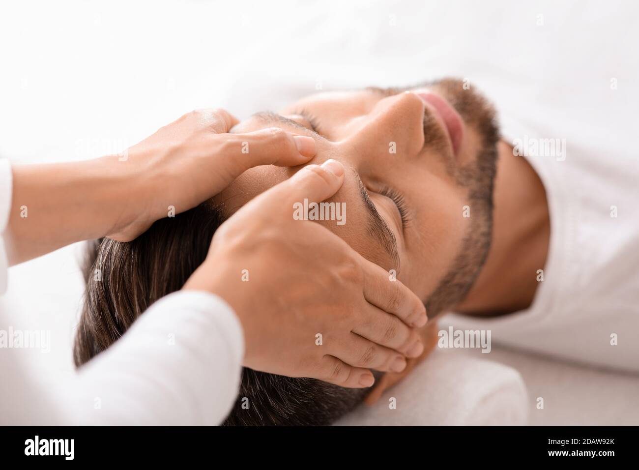 Friedlicher Mann bekommt eine heilende Kopfmassage im Spa Stockfoto