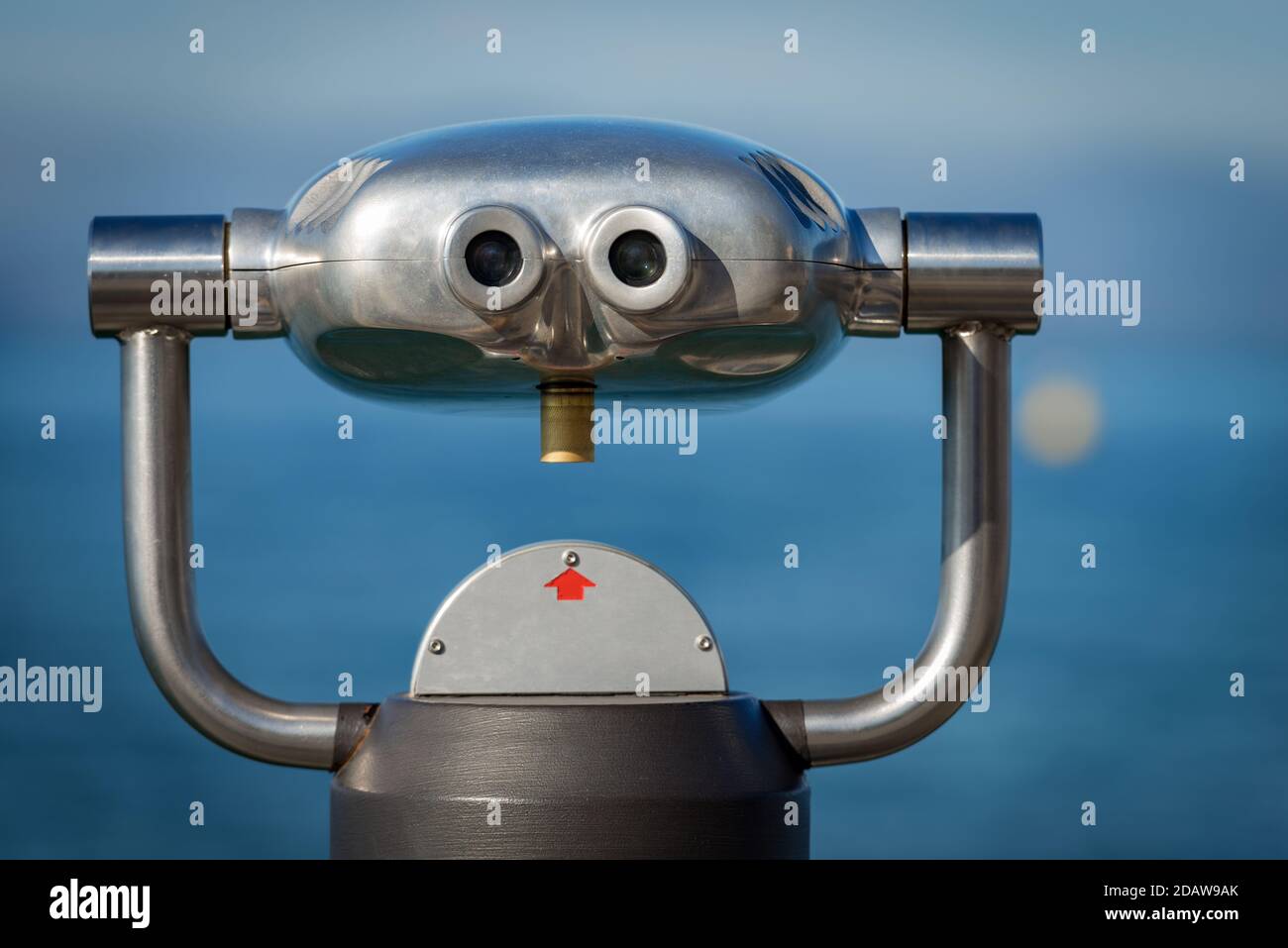 Nahaufnahme eines metallischen Münzfernglases für Touristen vor verschwommenem Hintergrund, Meer und Himmel Stockfoto