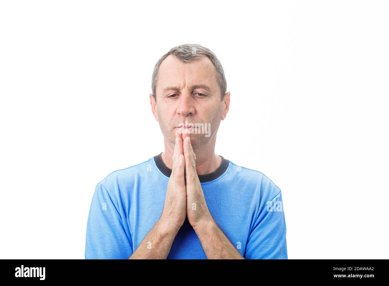 Deprimierter Mann mittleren Alters, der über weißem Hintergrund betet. Mann mittleren Alters beten um Hilfe mit einem verzweifelten Blick über weißen Hintergrund. Stockfoto