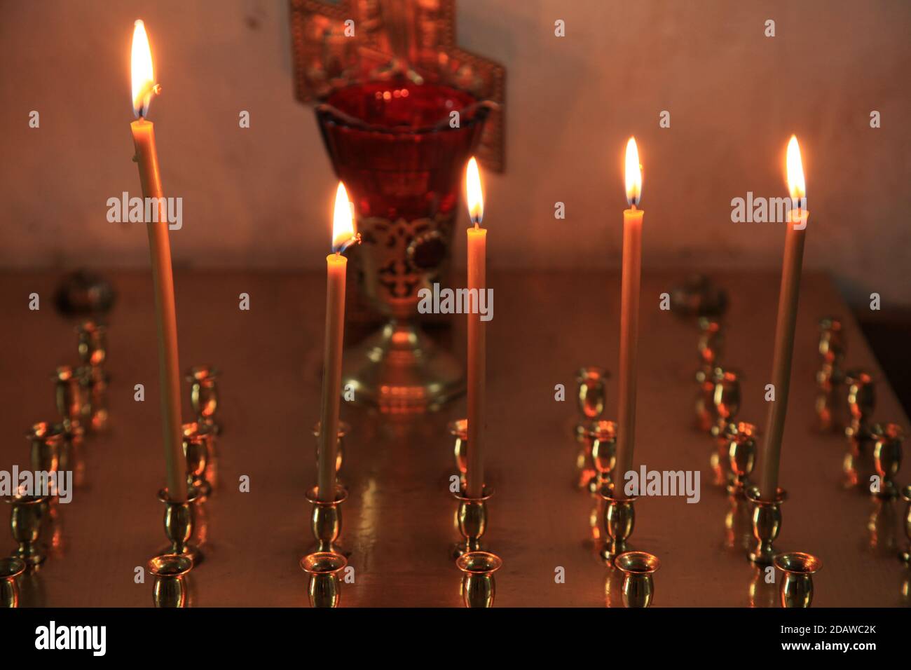 Feuer der Erinnerung. Sich Gott zuwenden. Stilles Gebet. Brennende Kerzen im Dunkeln vor dem Hintergrund der Ikonostase in der alten Kirche Stockfoto