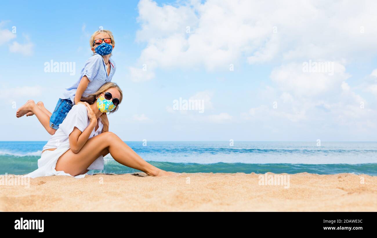 Mutter, Kind in Masken Spaß am Strand. Neue Regeln für das Tragen von Stoffbedeckungen an öffentlichen Orten. Stornierte Kreuzfahrt, Tour wegen Coronavirus COVID 19. Stockfoto