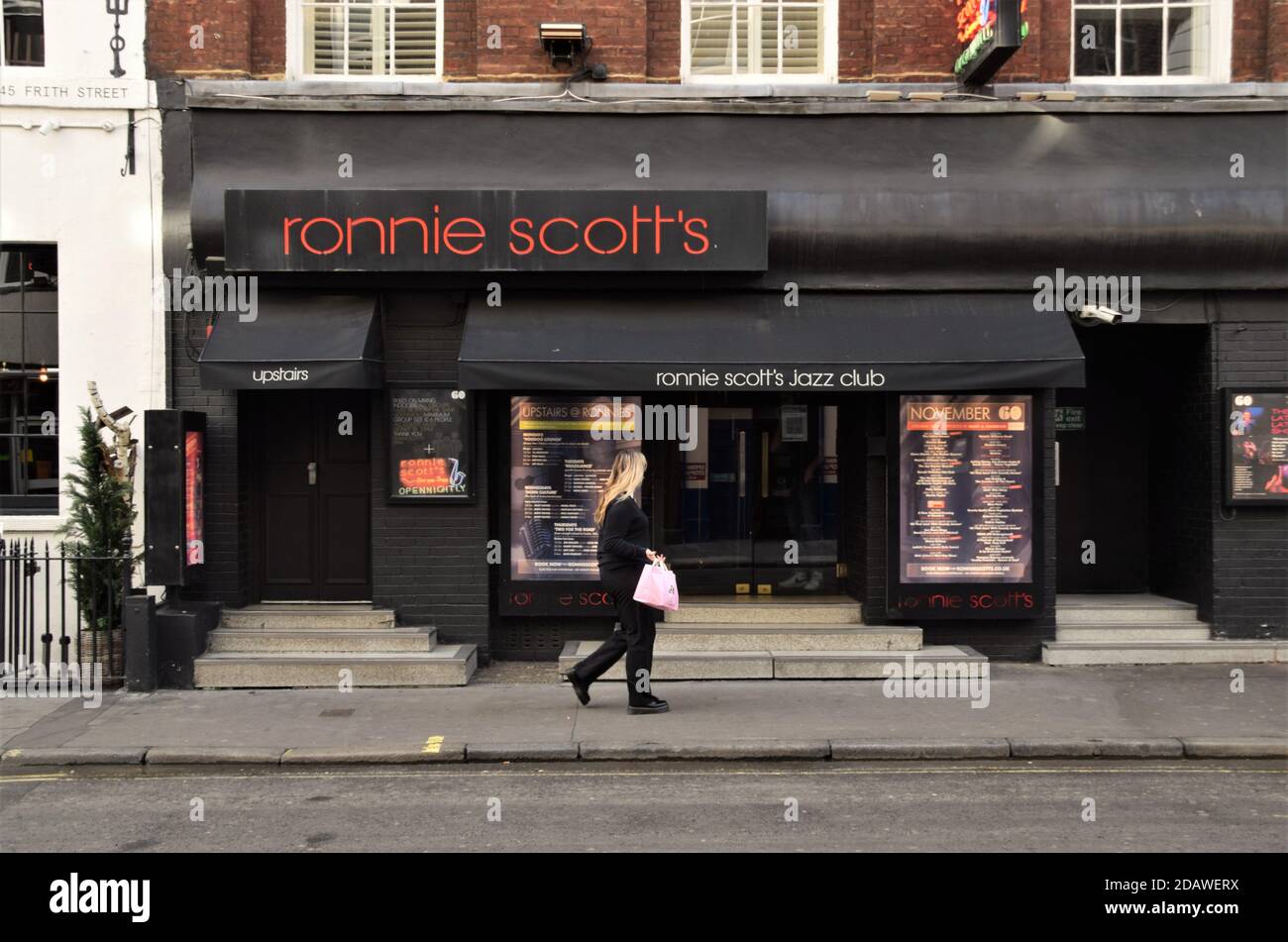 Eine Frau geht am Ronnie Scott's Jazz Club in Soho, London vorbei, der während der zweiten nationalen Sperre in England geschlossen wurde. Stockfoto