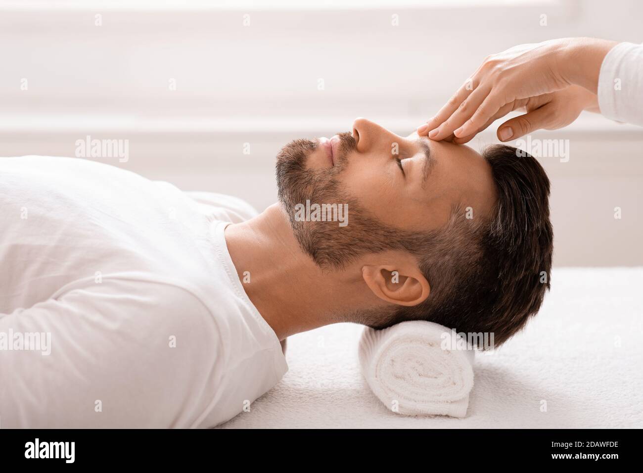 Massage Therapeut reiben entspannten Mann Stirn, Spa-Innenraum Stockfoto