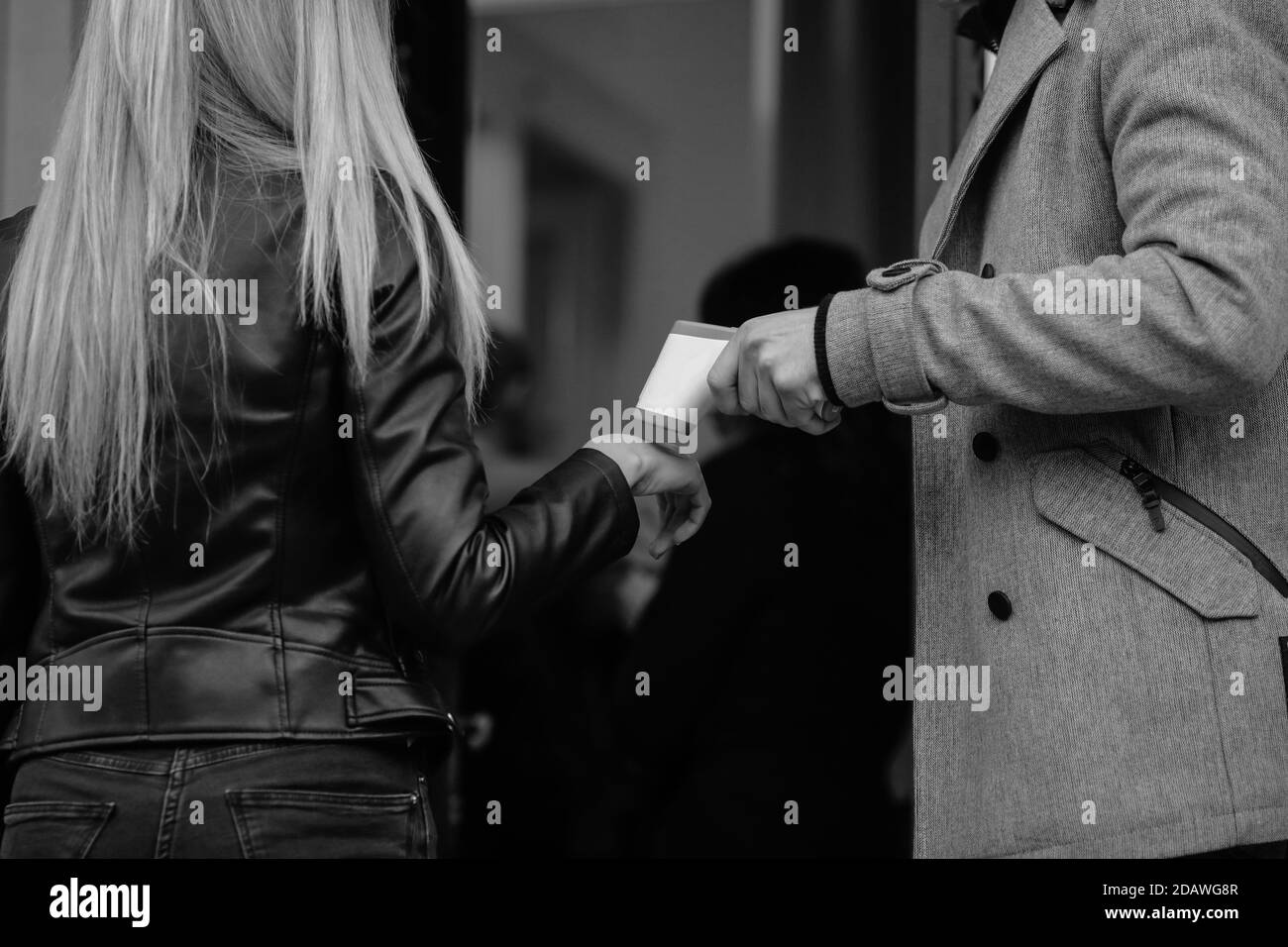 Details mit den Händen eines Mannes, der die Temperatur nimmt und auch die Hände von Personen desinfiziert, die eine öffentliche Einrichtung betreten. Stockfoto