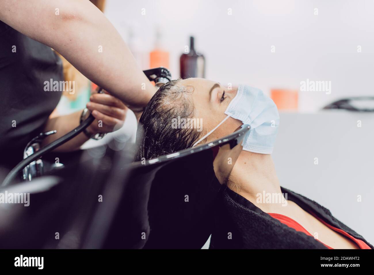 Frau mit Gesichtsmaske in einem Friseursalon während har Waschen Stockfoto