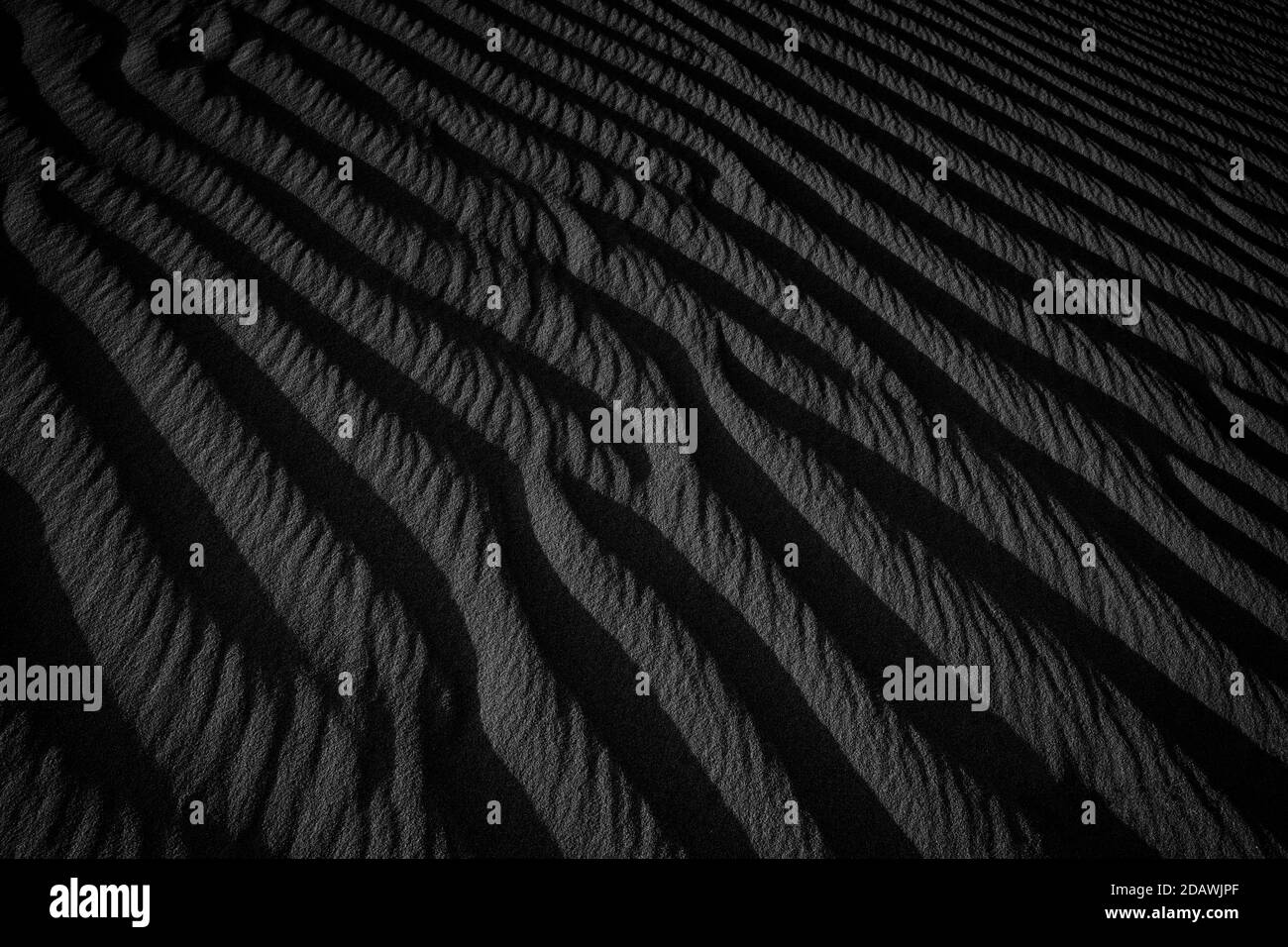 Makrofotografie mit schwarzem und weißem Sand am Strand. Textur von schwarz und whote Sand für den Hintergrund. Nahaufnahme Makroansicht der vulkanischen Sandoberfläche schwarz und w Stockfoto