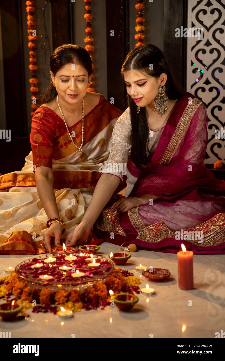 Eine indische Mutter und Tochter feiern das Festival of Lights, indem sie Kerzen und Diyas zu Hause anzünden, indische Familie feiert Diwali. Stockfoto