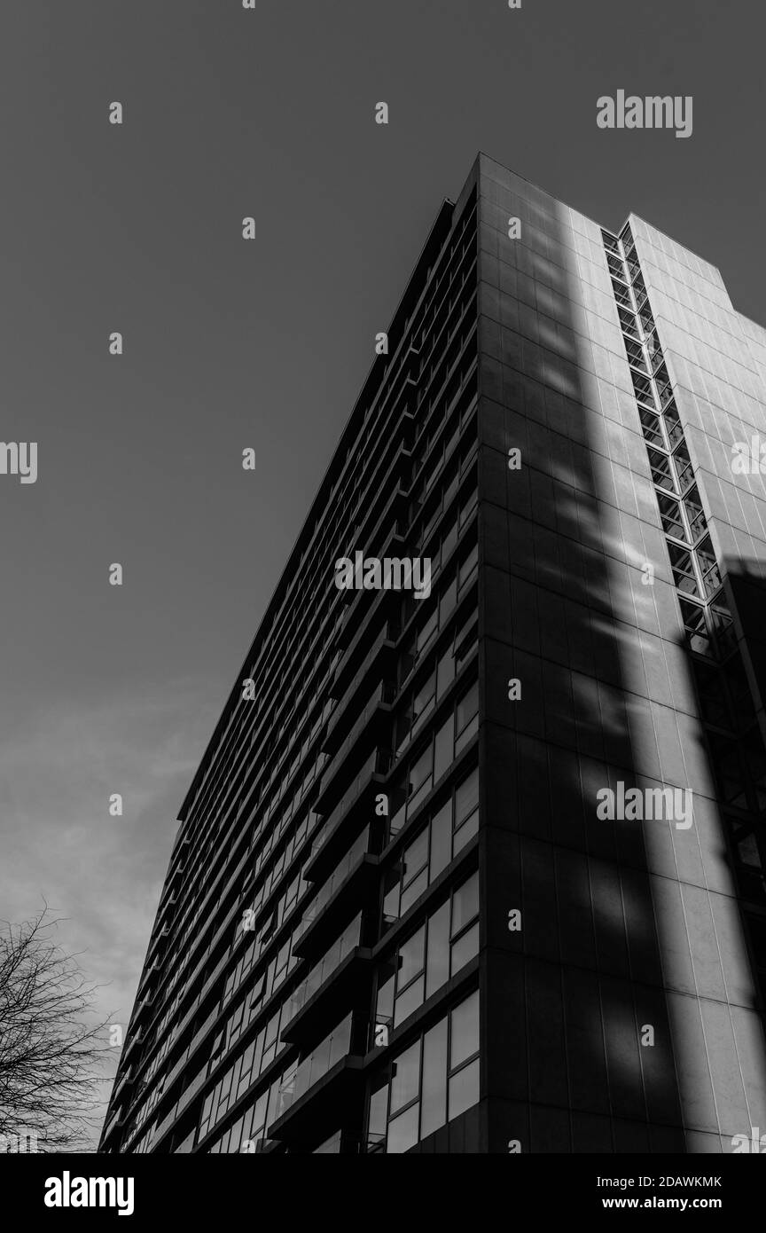 Schwarzweiß-Schwarzweißbild mit Blick auf eine Höhe Apartmentgebäude an einem klaren sonnigen Tag mit vertikalen Schatten Überwerfen Stockfoto